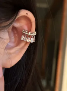 Detailed close-up of a sparkling silver pear-shaped zirconia ear cuff worn on a model's ear.