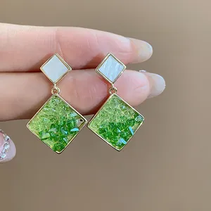 Nahaufnahme von 14 Karat vergoldeten Silbernadeloherringen mit grüner Glaseinlage