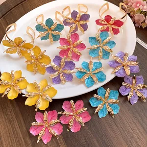 Vue détaillée de boucles d'oreilles fleurs froissées colorées à l'huile et métal