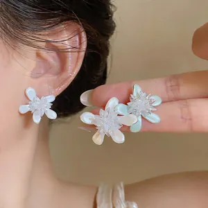 Close-up of elegant flower stud earrings in white and mint green finishes