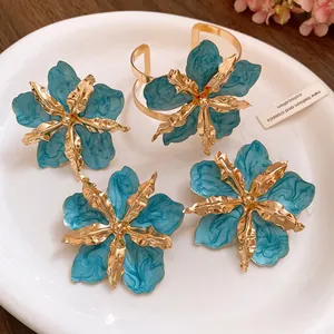Élégant ensemble de boucles d'oreilles et bracelet fleurs en émail bleu sur une assiette blanche
