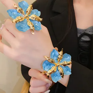 Détail d'un ensemble bague et bracelet fleur en émail bleu surdimensionné pour les vacances