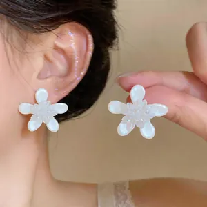 Detail view of white enamel flower earrings with a minimalist sweet style design