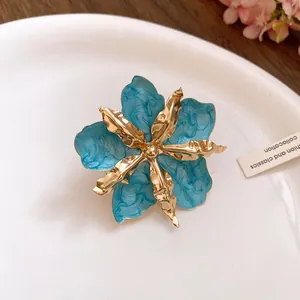 Gros plan d'une boucle d'oreille fleur bleue avec pétales dorés et émail