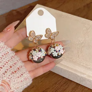 Eleganti orecchini a farfalla con sfere di fiori di cristallo in mano