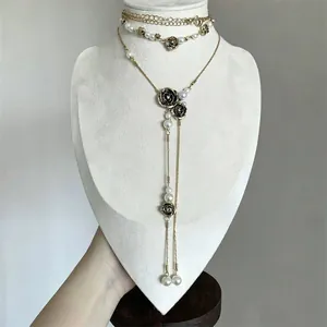 Detailed view of a vintage double-layer necklace with black roses, pearls and tassels.