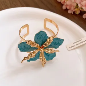 Détail d'un élégant bracelet jonc doré avec une fleur en émail bleu éclatant