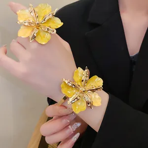 Détail rapproché d'une bague et d'un bracelet de luxe en émail jaune plissé et métal doré