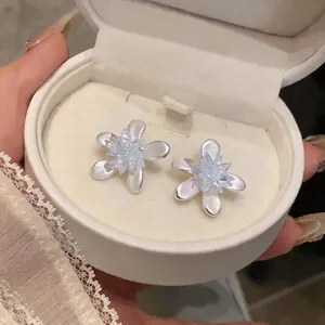 Close-up of elegant white flower stud earrings with crystal centers in a gift box