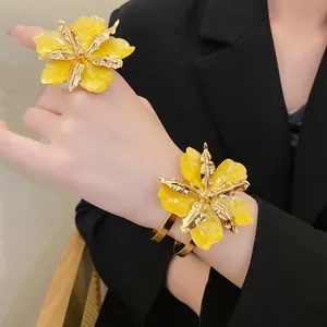 Ensemble bague et bracelet fleur jaune froissée porté avec un blazer noir chic