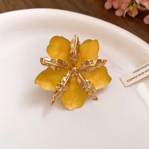 Gros plan sur une boucle d'oreille fleur jaune avec pétales en métal doré froissé