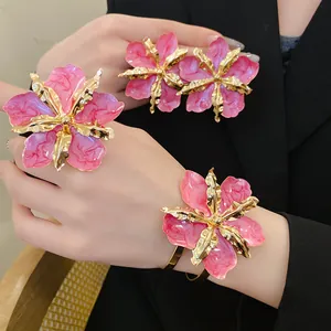 Vue détaillée d'un ensemble de bijoux fleurs en émail rose et accents dorés sur modèle