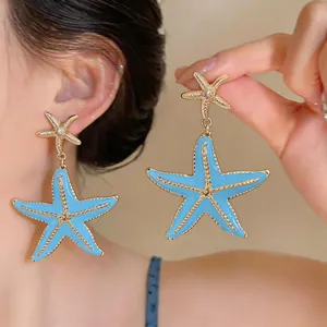 Elegant beach-style light blue enamel starfish drop earrings with gold-plated finish details.