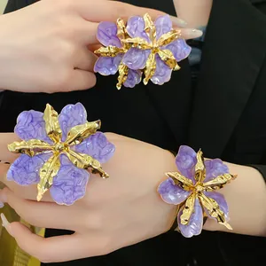 Gros plan de bijoux en fleurs plissées violettes avec cadre en métal doré et émail