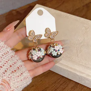 Primo piano di eleganti orecchini a farfalla dorati con delicati dettagli floreali in strass