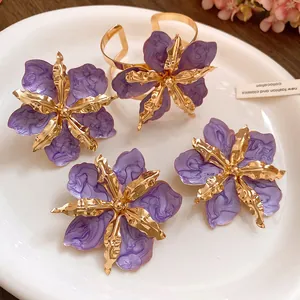 Détails de boucles d'oreilles fleurs mauves avec des accents dorés sur une assiette