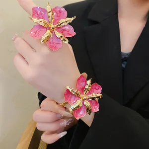 Vue détaillée d'un ensemble de bijoux fleur en émail rose avec bague et bracelet porté