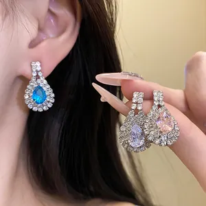 Detailed close-up showing rhinestone teardrop dangle earrings in blue, clear, and pink colors.