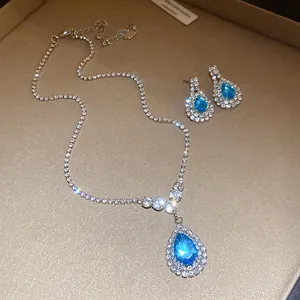 Macro view of blue teardrop pendant necklace and matching earrings set with rhinestones