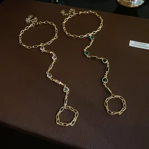 Detailed view of vintage gold-toned slave bracelets with emerald and clear heart gems.