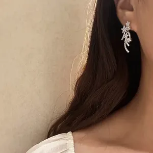 Close-up detailed view of luxury zircon star meteor clip-on earrings worn by an Asian model