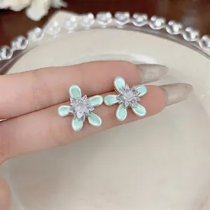 Detailed close-up of light green flower stud earrings featuring glass oil drip petals