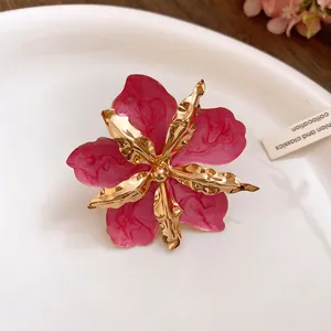 Gros plan détaillé montrant l'émail rose marbré et les pétales métalliques dorés de boucles d'oreilles