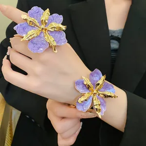 Détail d'une bague et d'un bracelet fleurs en émail violet avec finitions dorées