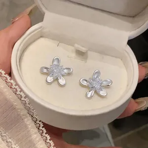 Exquisite silver-tone flower stud earrings with a sparkling crystal center in a white jewelry box