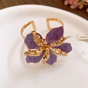 Bracelet jonc doré élégant orné d'une grande fleur en émail plissé de couleur violet.