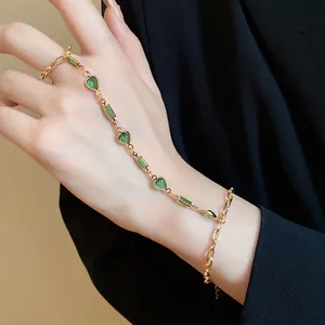 Elegant vintage gold hand chain featuring green resin hearts and emerald cut accents.