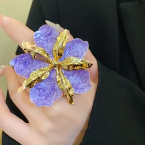 Vue détaillée de la boucle d'oreille fleur plissée violette avec détails métalliques dorés