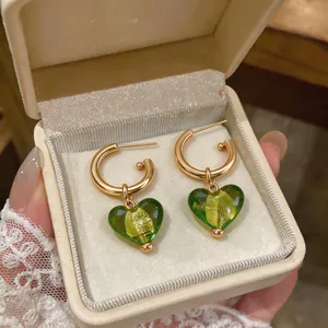 Vue détaillée des boucles d'oreilles cœur en résine verte dans une boîte à bijoux