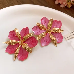 Gros plan détaillé de boucles d'oreilles fleur rose avec pétales dorés texturés