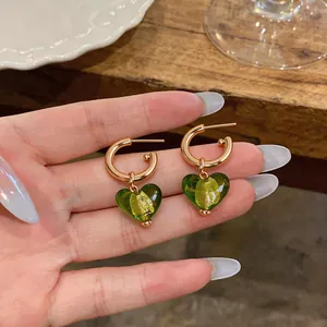 Une vue détaillée de boucles d'oreilles créoles dorées avec pendentifs cœur en verre