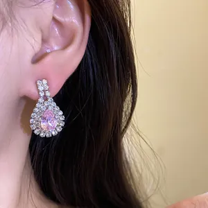 Detailed close-up showing an elegant pink pear-shaped rhinestone drop earring worn on the ear