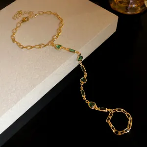 Detailed view of a vintage gold-toned hand harness with green resin heart charms.