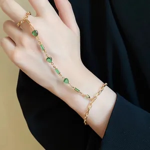 Close-up detail of a gold vintage style hand chain featuring green resin hearts.