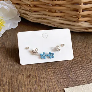 Detail showing rhinestone butterfly and blue enamel flower studs on a display card.