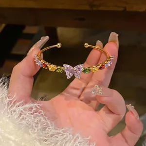 Elegant gold plated cuff bracelet featuring colorful zircon stones and a purple butterfly motif