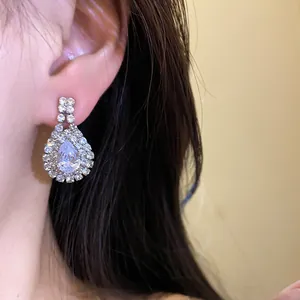 Detailed macro view of teardrop rhinestone drop earrings with a sparkling finish.