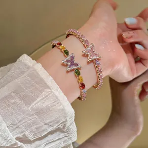 Close-up of elegant butterfly open bangles with colorful teardrop zircons on a wrist.