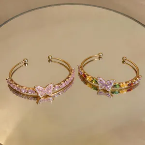 Detailed view of two gold-plated butterfly bracelets with colorful teardrop zircons