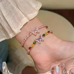 Close-up of elegant gold butterfly bangles with colorful zircon stones on wrist