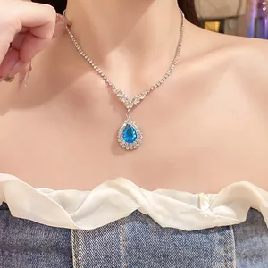 Elegant silver-tone necklace with blue teardrop pendant worn by model for detail view