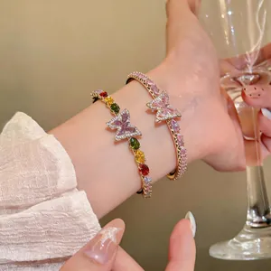 Close-up of elegant butterfly bangles with colorful and pink zircons on wrist.