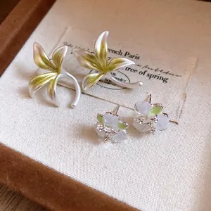 Elegant forest style flower earrings with delicate green and white floral stud designs.
