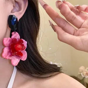 Close-up detail of vibrant pink and red layered acrylic flower drop earrings worn on model