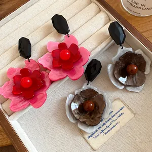Close-up of retro acrylic flower drop earrings in pink and brown tones on jewelry tray