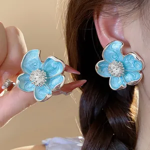 Gros plan d'élégantes boucles d'oreilles clips fleurs bleu clair avec détails métalliques